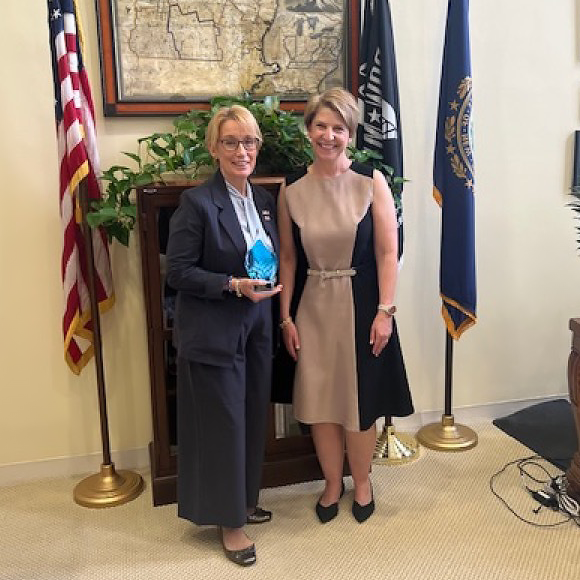 Photo of Senator Hassan holding the UDL Policy Award, next to CAST CEO Lindsay Jones in a White House office