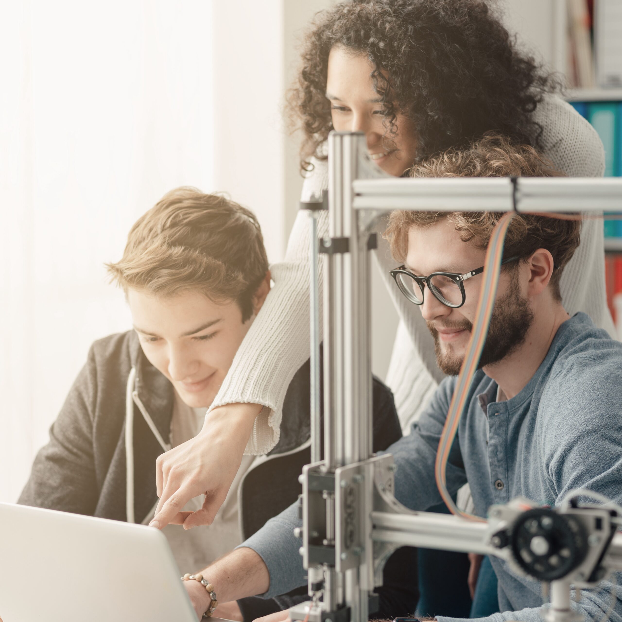 Three young professionals in a lab looking at a laptop