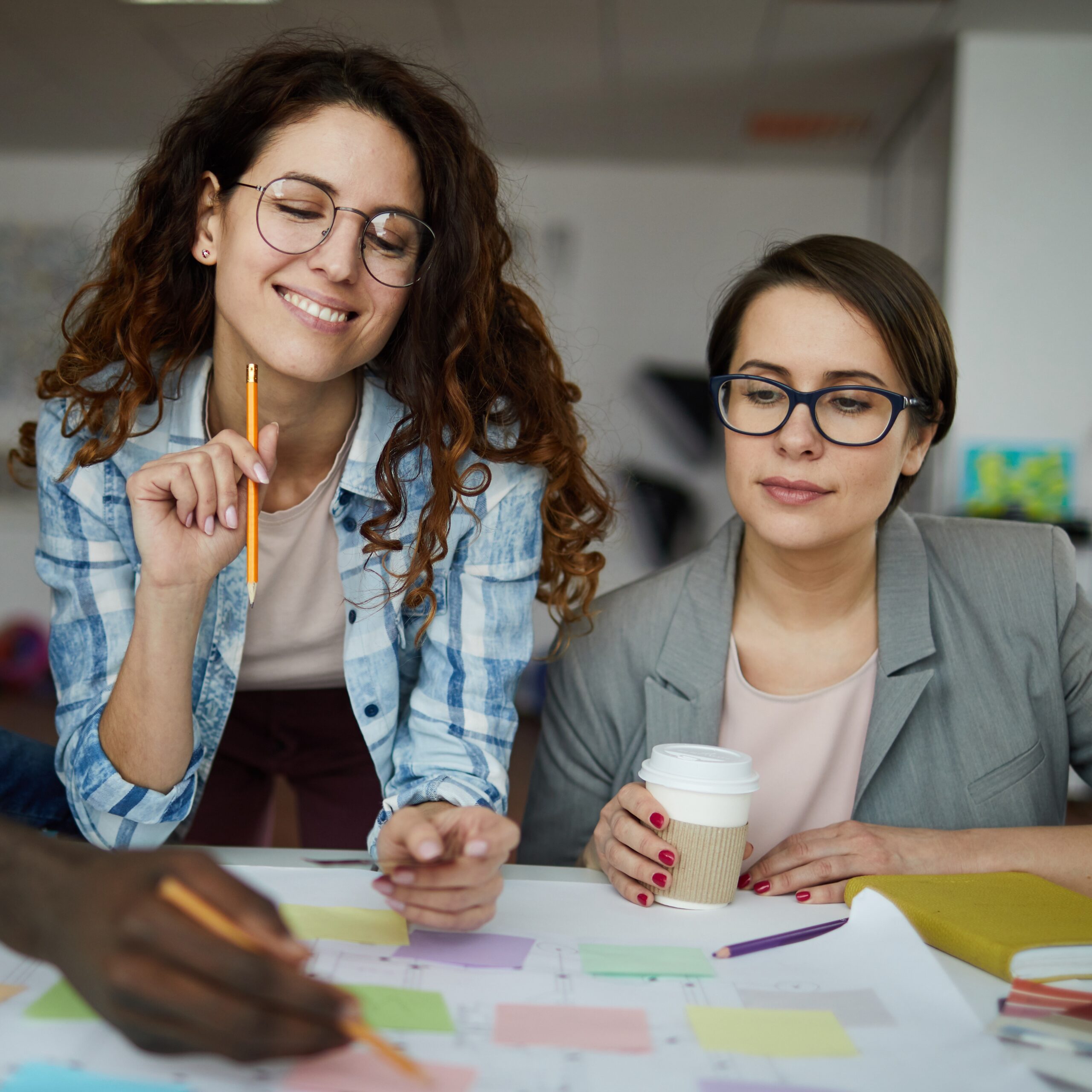 Two women looking over a board with post it notes