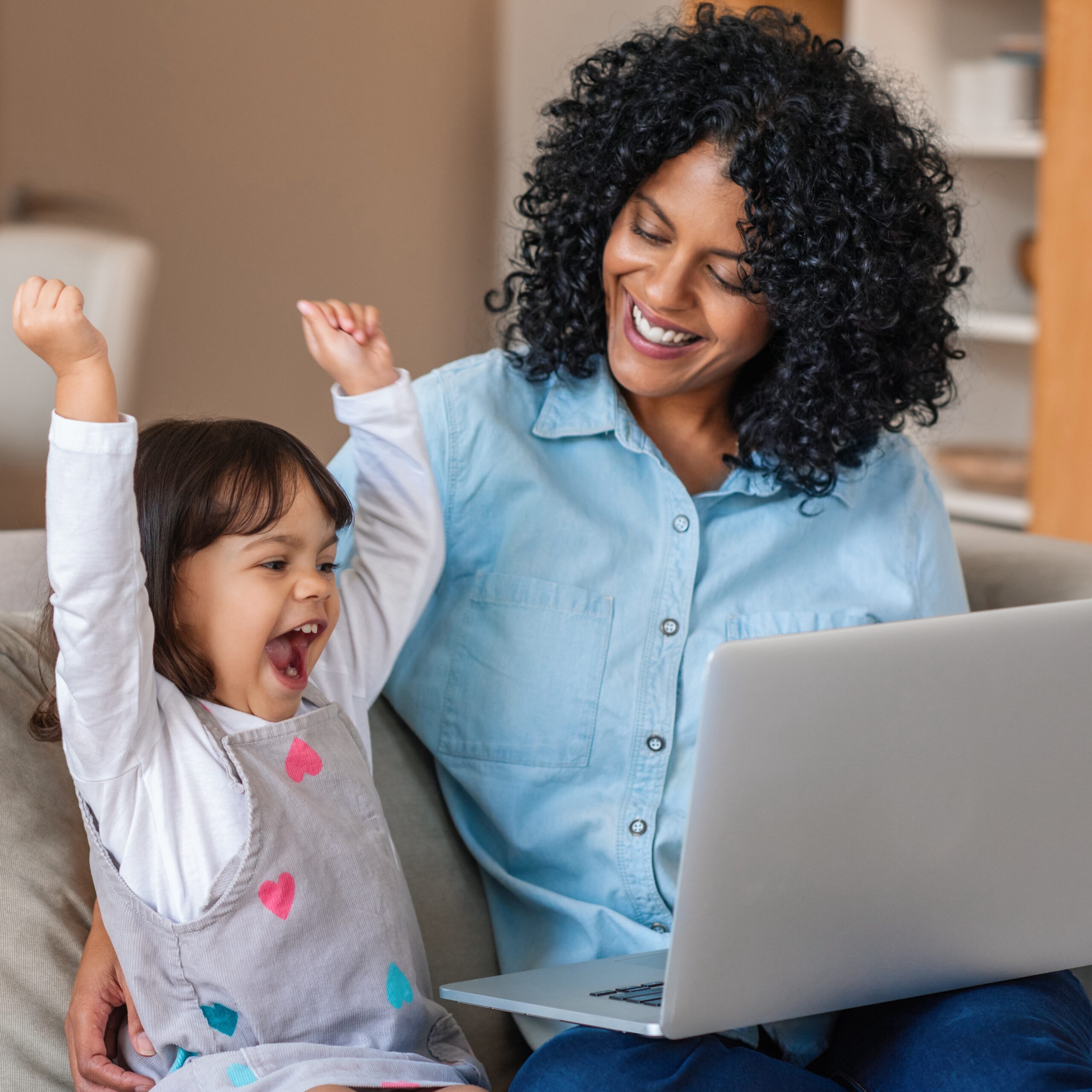 Laughing little girl and mother watching something on a laptop