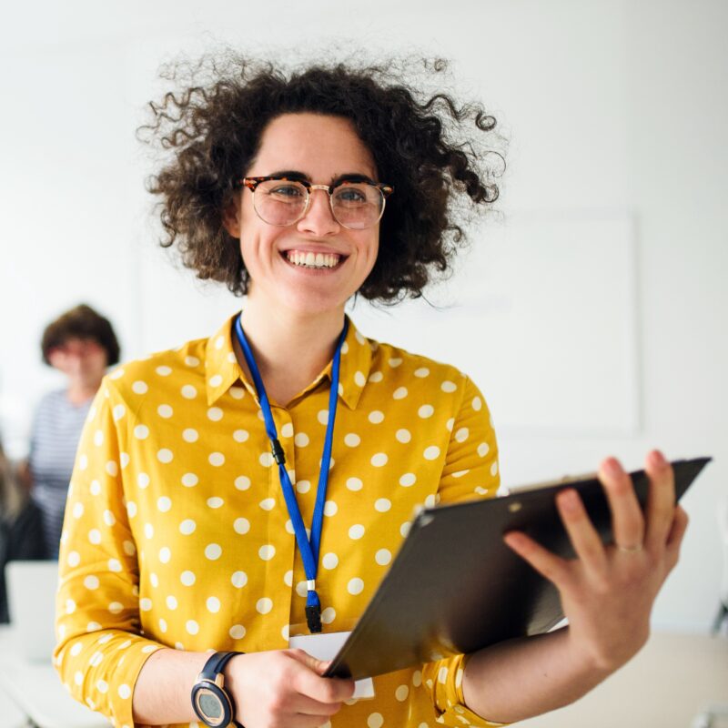 Young woman with curly hair smiling while holding a laptop