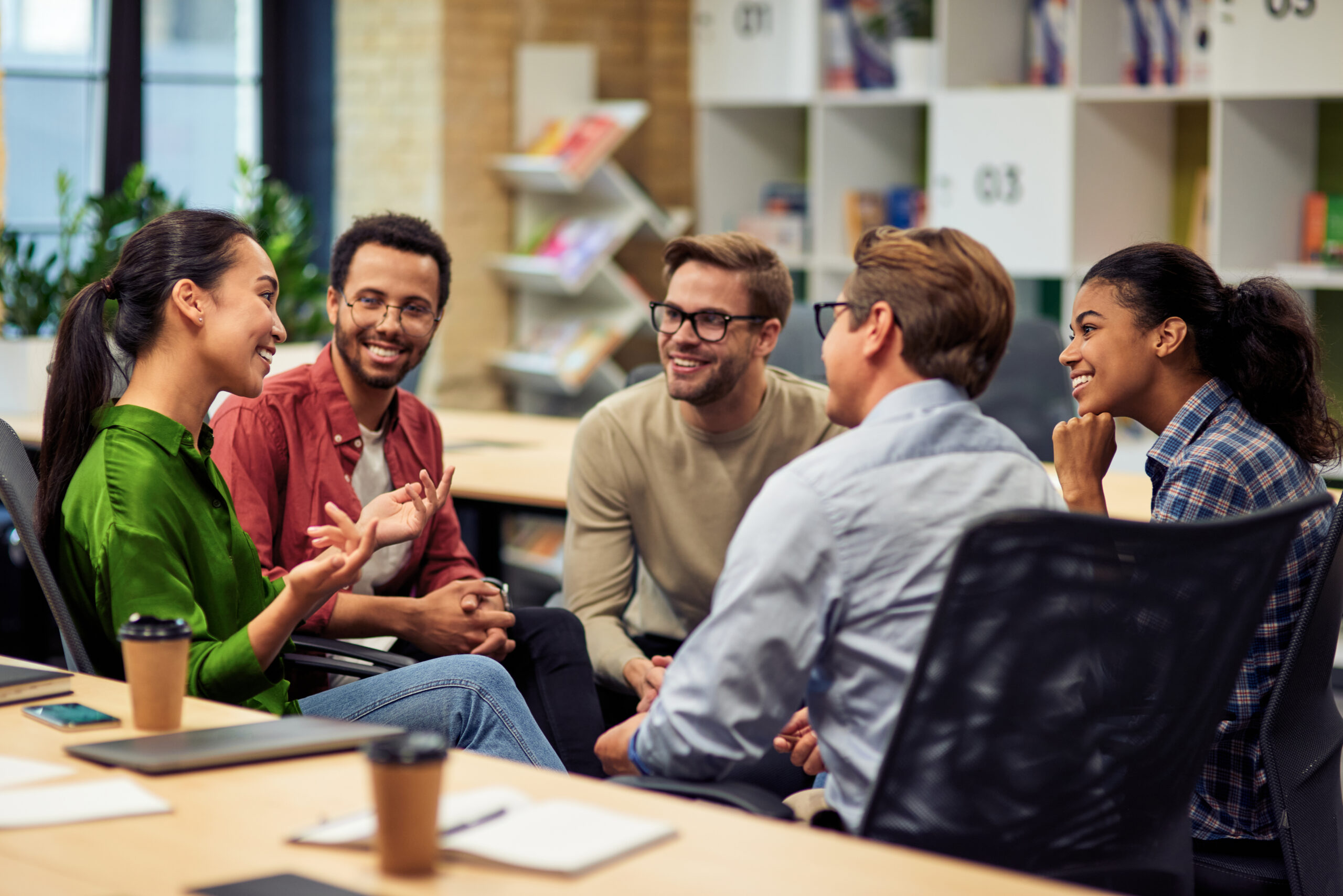 Creating success. Group of young happy multi racial business people communicating and sharing ideas while working together in the modern office. Teamwork and cooperation concept