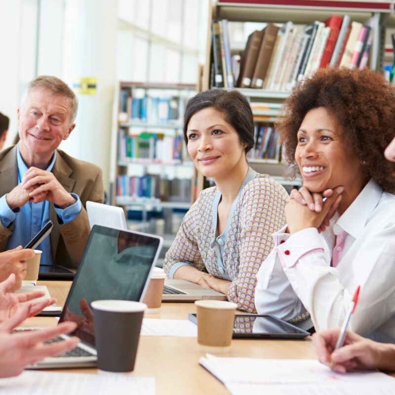 Group Of Mature Students Collaborating On Project In Library