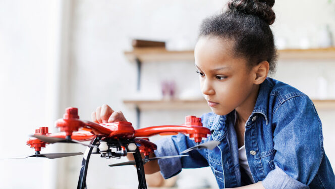 Photo of a young girl exploring the parts of a drone