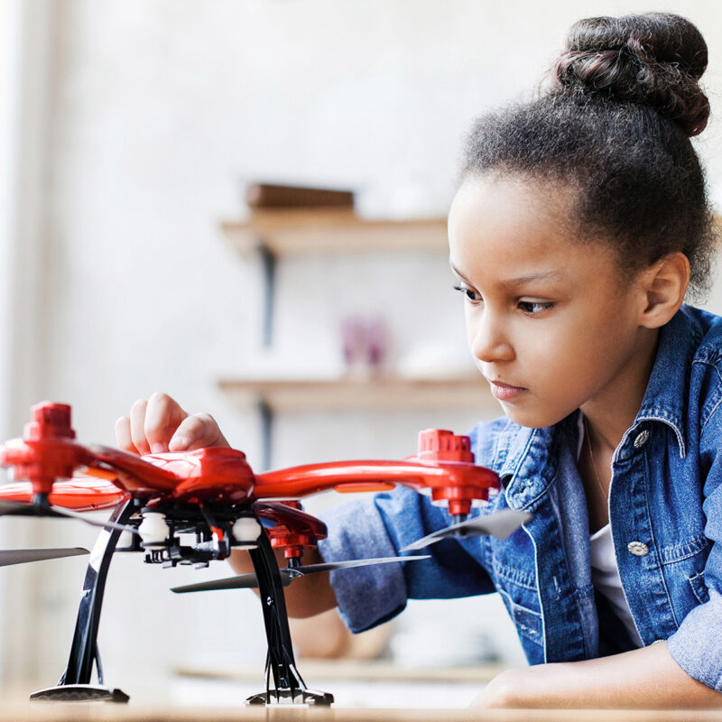 Photo of a young girl exploring the parts of a drone