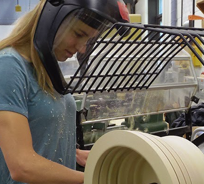 Young person with a protective visor and helmet working with a large power tool