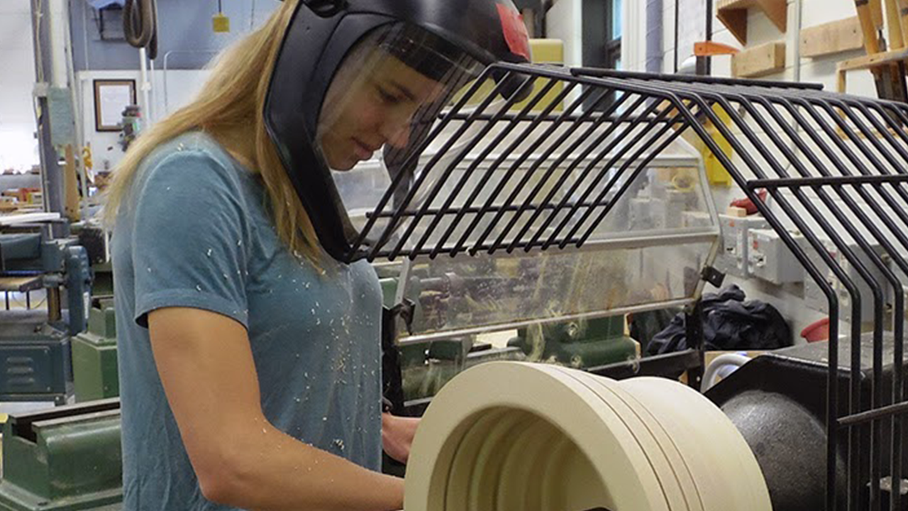 Young person with a protective visor and helmet working with a large power tool